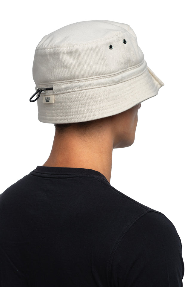 Three quarter back view of tapered bucket hat in bone colorway on model.