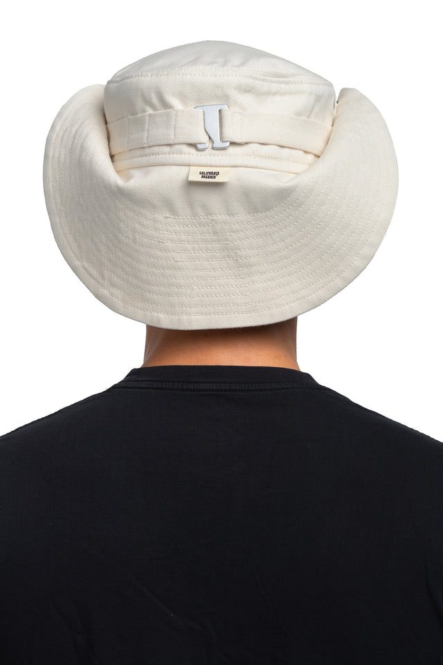 Back view of floppy bucket hat in bone/eggshell colorway worn on model with side of hat snapped up to show convertibility of style.