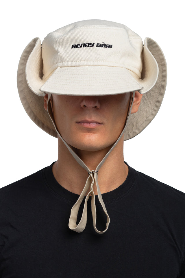 Front view of floppy bucket hat in bone/eggshell colorway worn on model with side of hat snapped up to show convertibility of style.