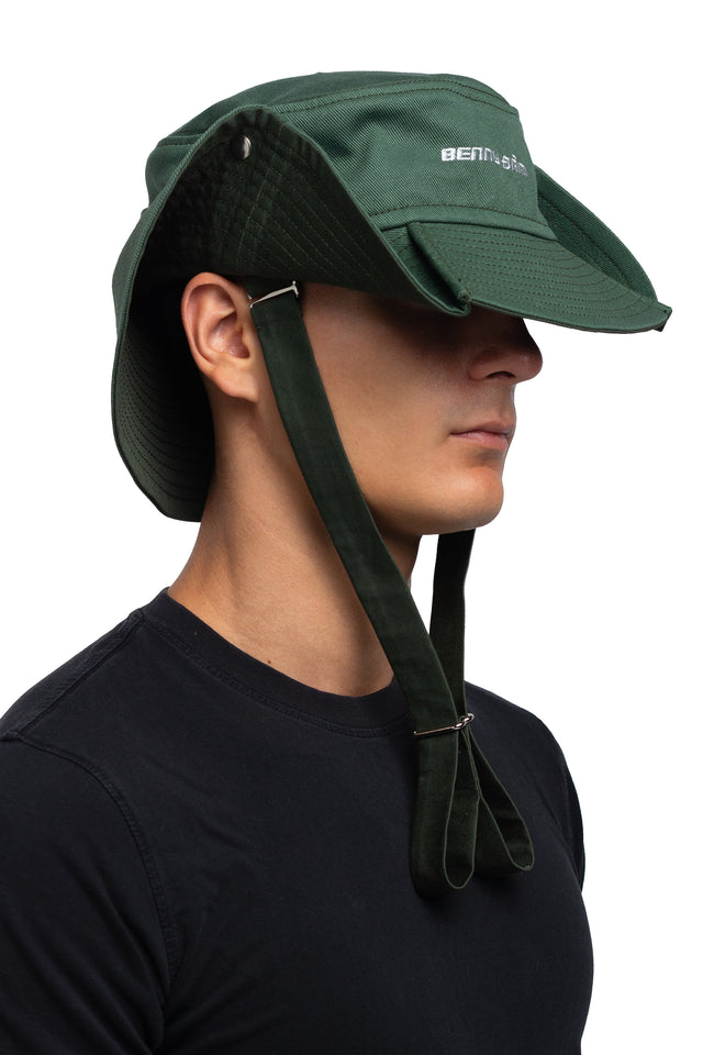 Three quarter front view of floppy bucket hat in evergreen/pine colorway worn on model with side of hat snapped up to show convertibility of style.