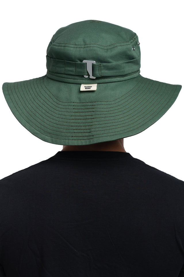 Back view of floppy bucket hat in evergreen/pine colorway worn on model with side of hat unsnapped in natural state.