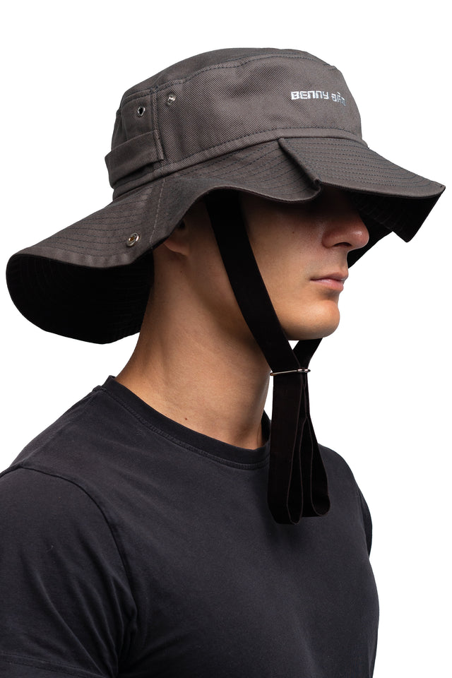 Three quarter front view of floppy bucket hat in graphite/espresso colorway worn on model with side of hat unsnapped in natural state.