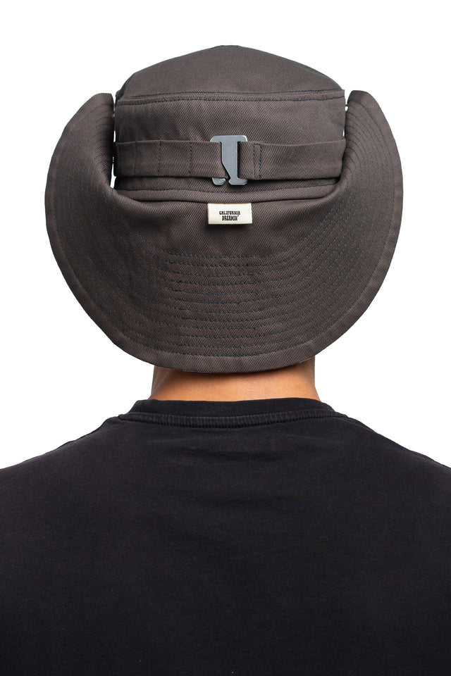 Back view of floppy bucket hat in graphite/espresso colorway worn on model with side of hat snapped up to show convertibility of style.