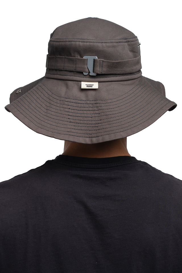 Back view of floppy bucket hat in graphite/espresso colorway worn on model with side of hat unsnapped in natural state.