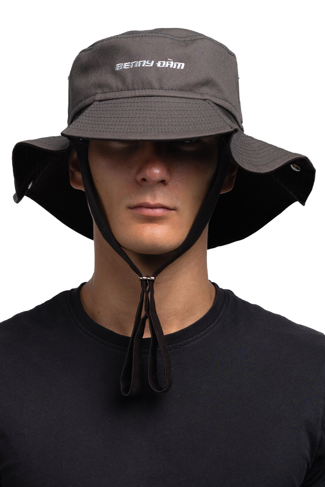 Three quarter front view of floppy bucket hat in graphite/espresso colorway worn on model with side of hat unsnapped in natural state.
