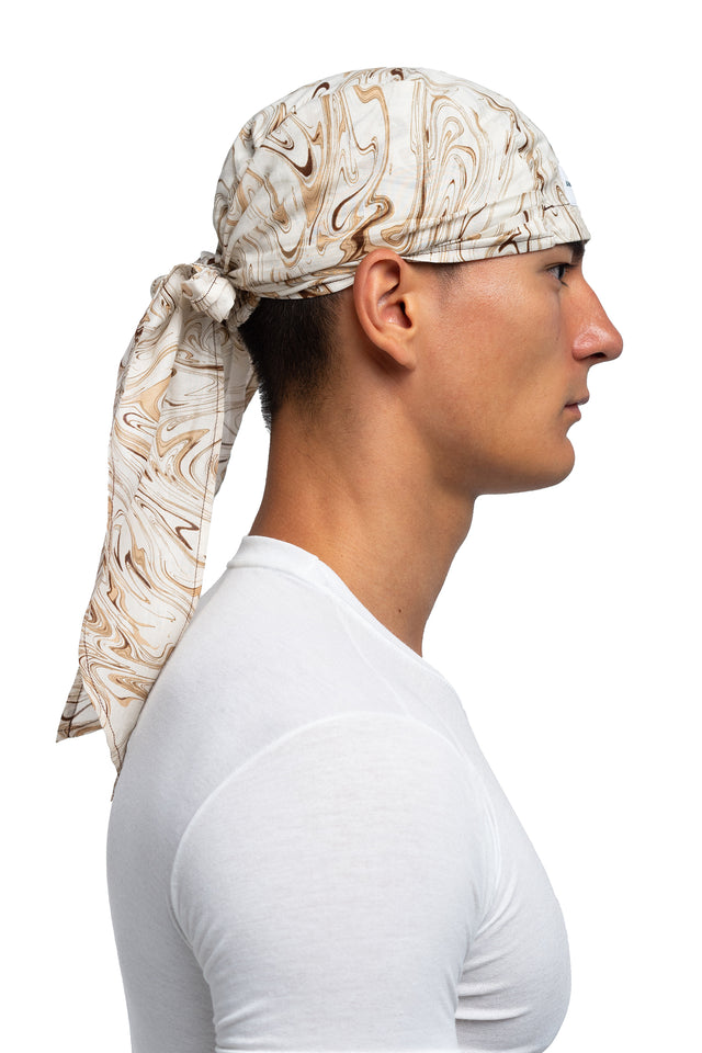 Side view of brown & cream colorway bandana hat worn on model.