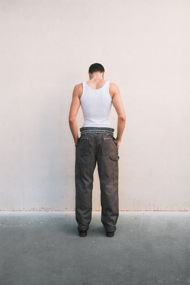 Model with is back to camera wearing white tank and convertible coverall pants variation in graphite colorway.