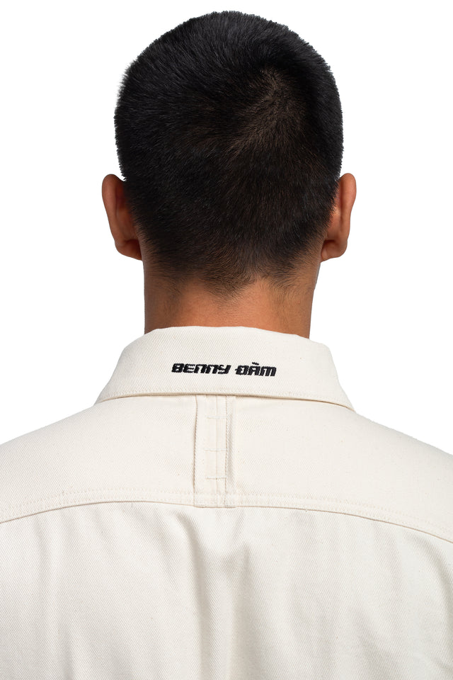 Close up back view of convertible coverall embroidery on collar in bone colorway on model.